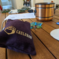 A table with various roleplaying accessories on it, including a Cauldron dice bag